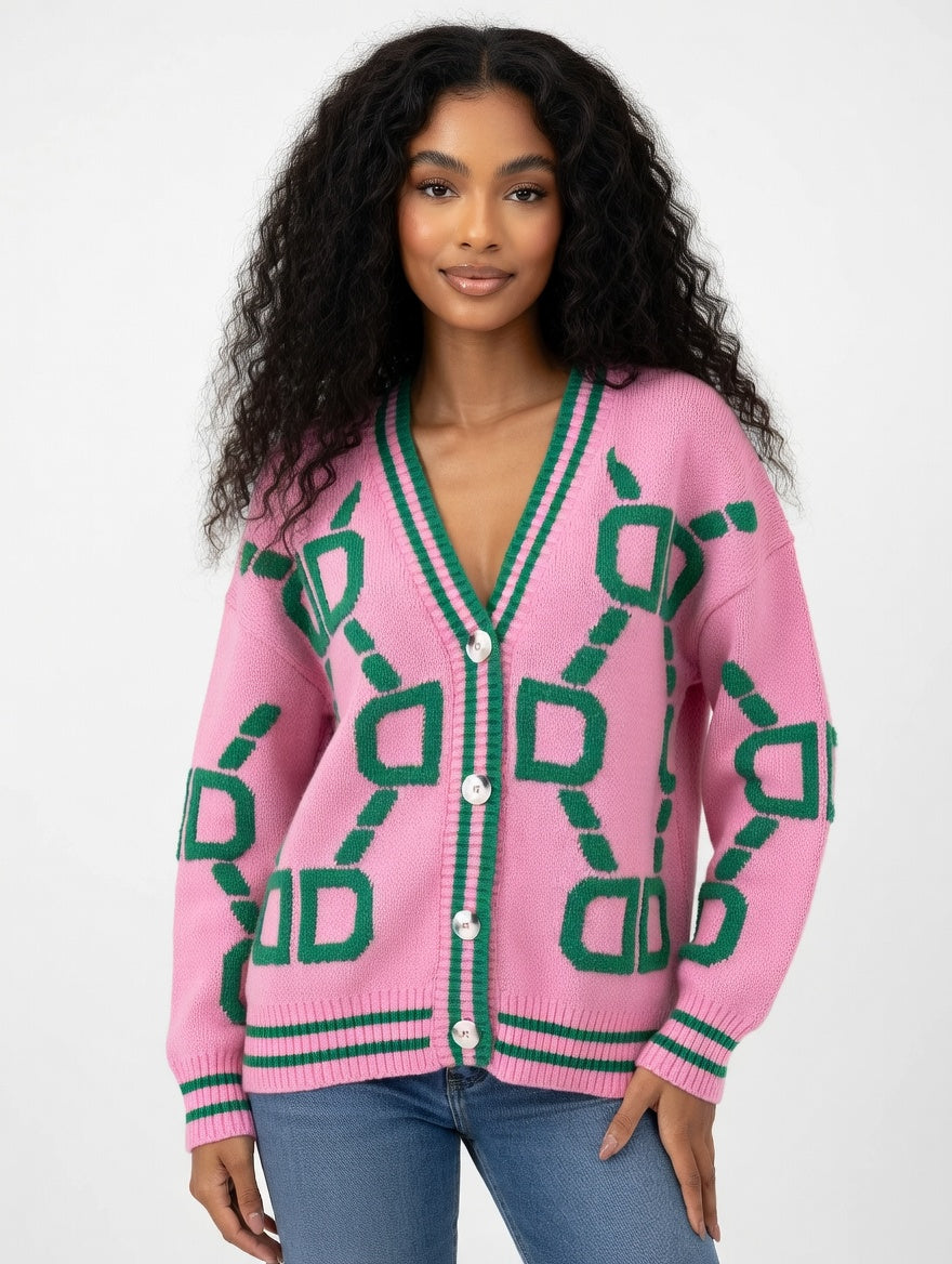 Woman wearing a pink cardigan with green geometric patterns on a white background
