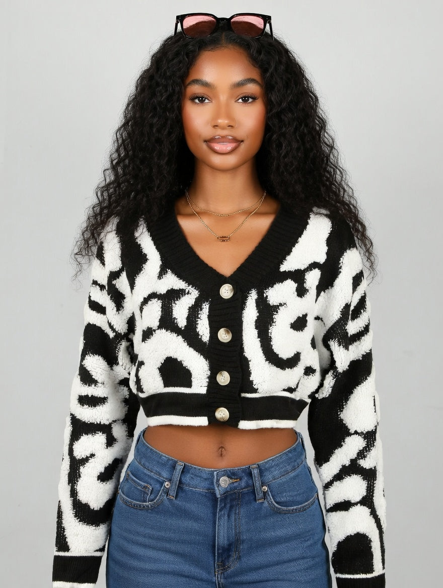 Woman wearing a black and white patterned cardigan with blue jeans on a gray background