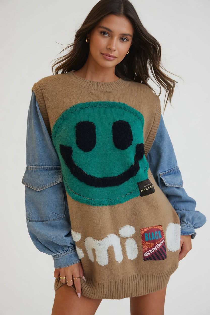 Woman wearing a unique sweater with a smiley face design and denim jacket.