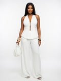Woman wearing a white sleeveless top and wide-leg pants on a white background