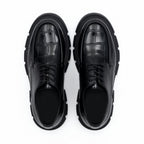 Pair of black leather shoes with chunky soles on a white background