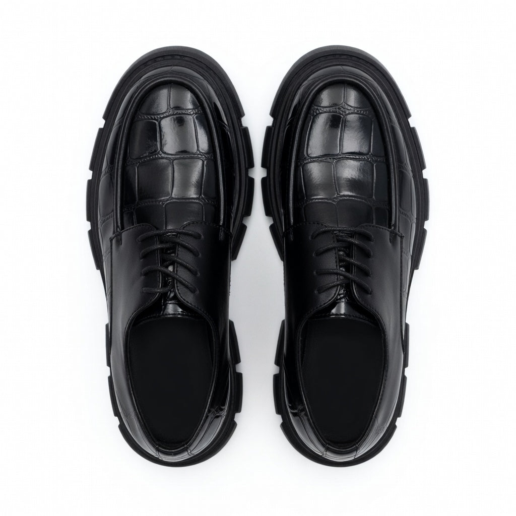 Pair of black leather shoes with chunky soles on a white background