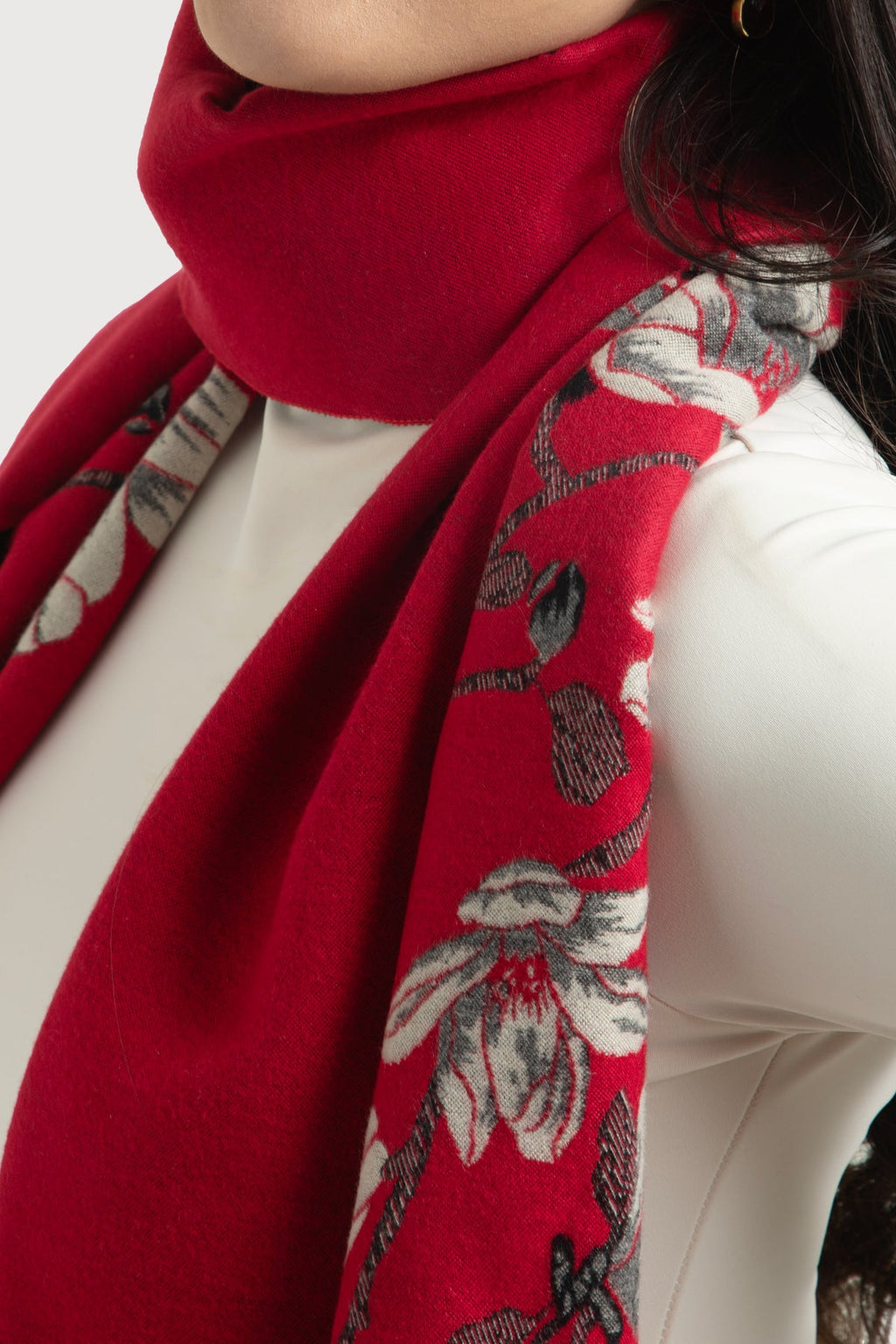 Red floral-patterned scarf draped around a person's neck on a white background
