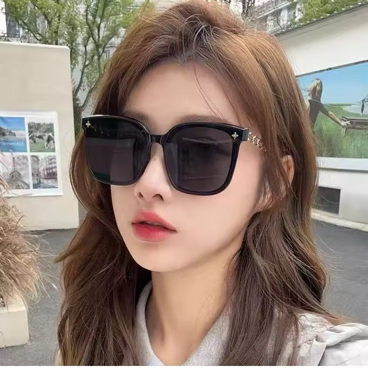 Woman wearing black sunglasses with a blurred outdoor background