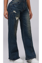 Person wearing distressed blue jeans on a plain background