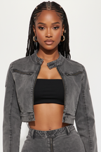 Woman wearing a gray denim jacket and pants with a black top on a white background