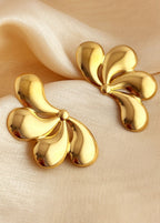 Gold earrings on a beige fabric background