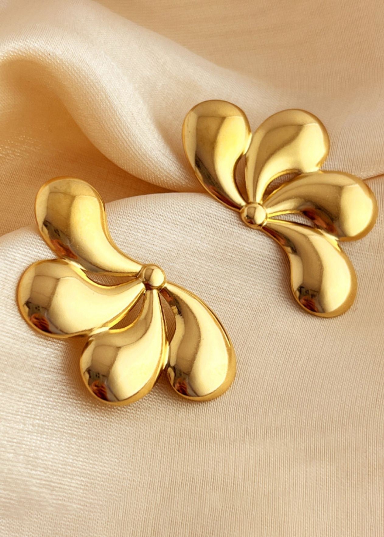 Gold earrings on a beige fabric background
