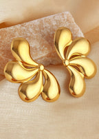 Gold flower-shaped earrings on a beige fabric background