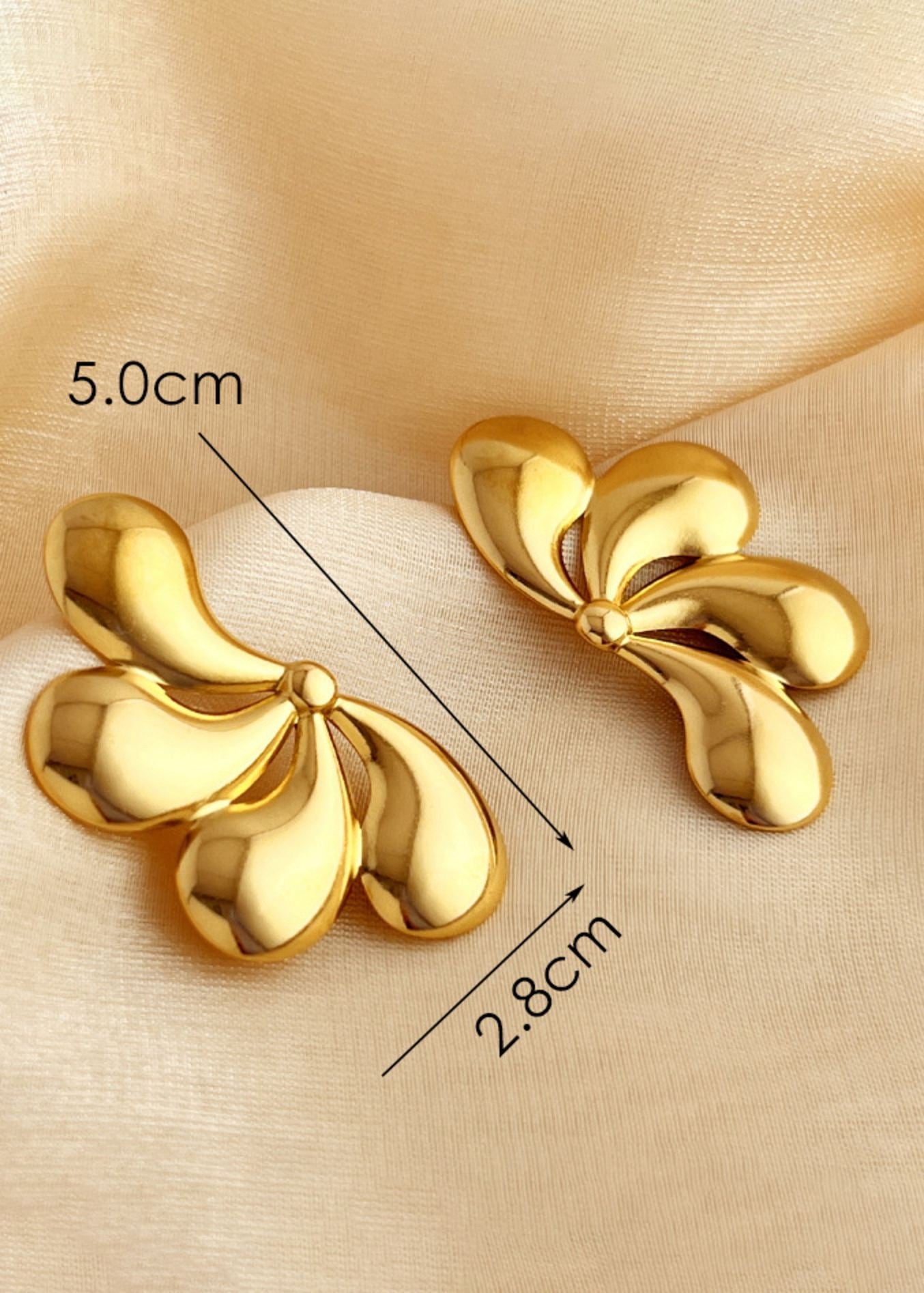 Gold earrings on a beige fabric background with measurements indicated.