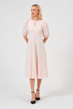 Woman wearing a light pink dress with puff sleeves on a white background