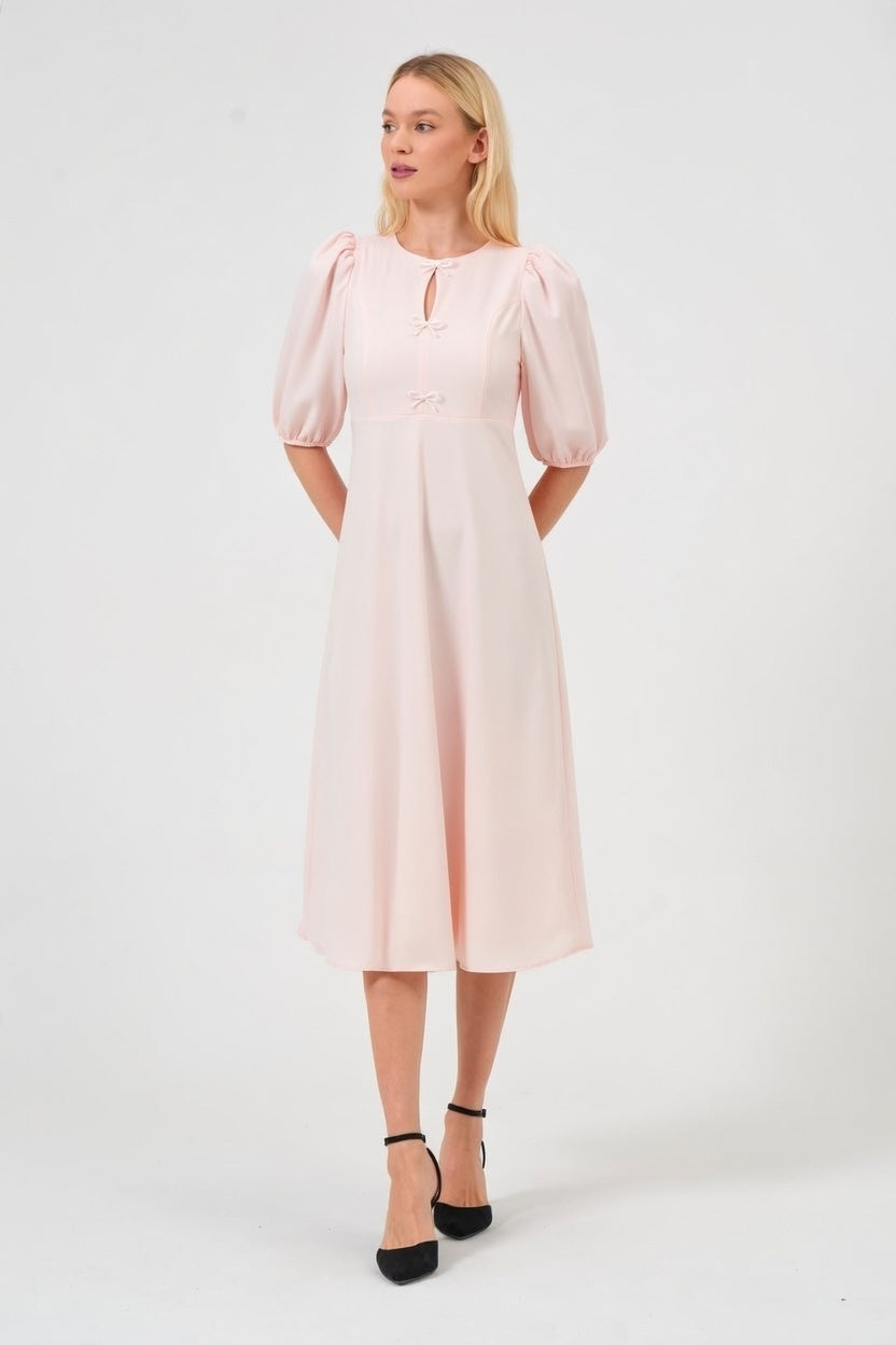 Woman wearing a light pink dress with puff sleeves on a white background
