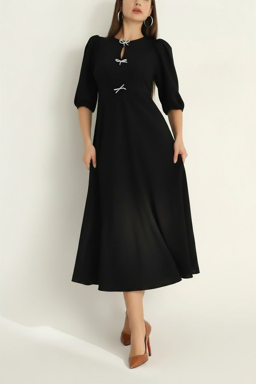 Black dress with puff sleeves worn by a model on a white background