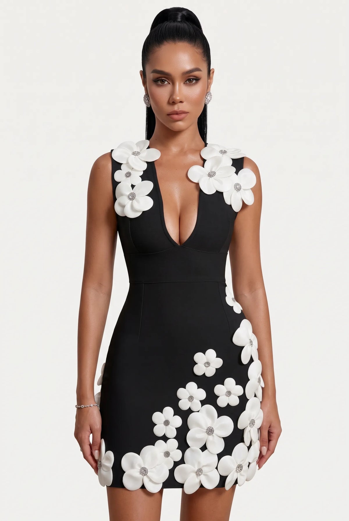 A woman modeling a black bodycon mini dress with large white 3D floral appliqués on the bodice and skirt, paired with white heeled sandals, against a plain white studio background.