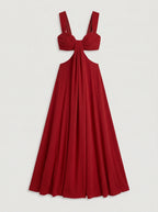The dress shown is a crimson red maxi dress featuring side cutouts at the waist, a structured sweetheart bustier top with gathered drape detail, wide shoulder straps, and a bow tie backclosure.