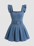 Model wearing a short-sleeved denim mini dress is crafted from a medium-blue wash denim featuring a structured, square-necked bodice with molded, bustier-style seaming and playful ruffled shoulder straps. Designed with a fitted waist cinched by a matching fabric belt with a metallic buckle, the dress flows down into a flared, pleated skater skirt that creates a crisp, youthful silhouette.