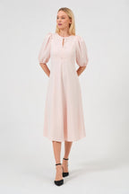 Woman wearing a light pink dress with puff sleeves on a white background
