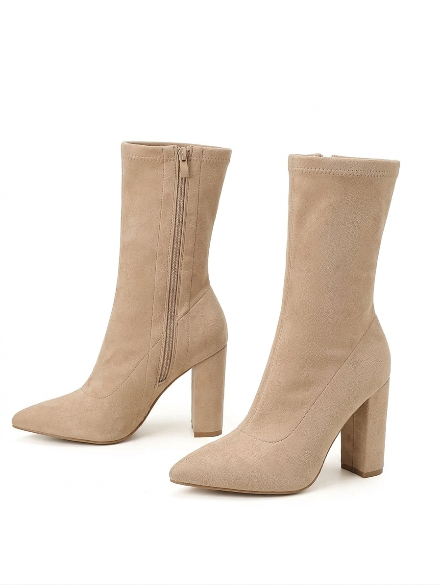 Pair of beige knee-high boots with a block heel on a white background