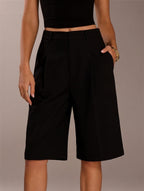 Person wearing black shorts on a neutral background