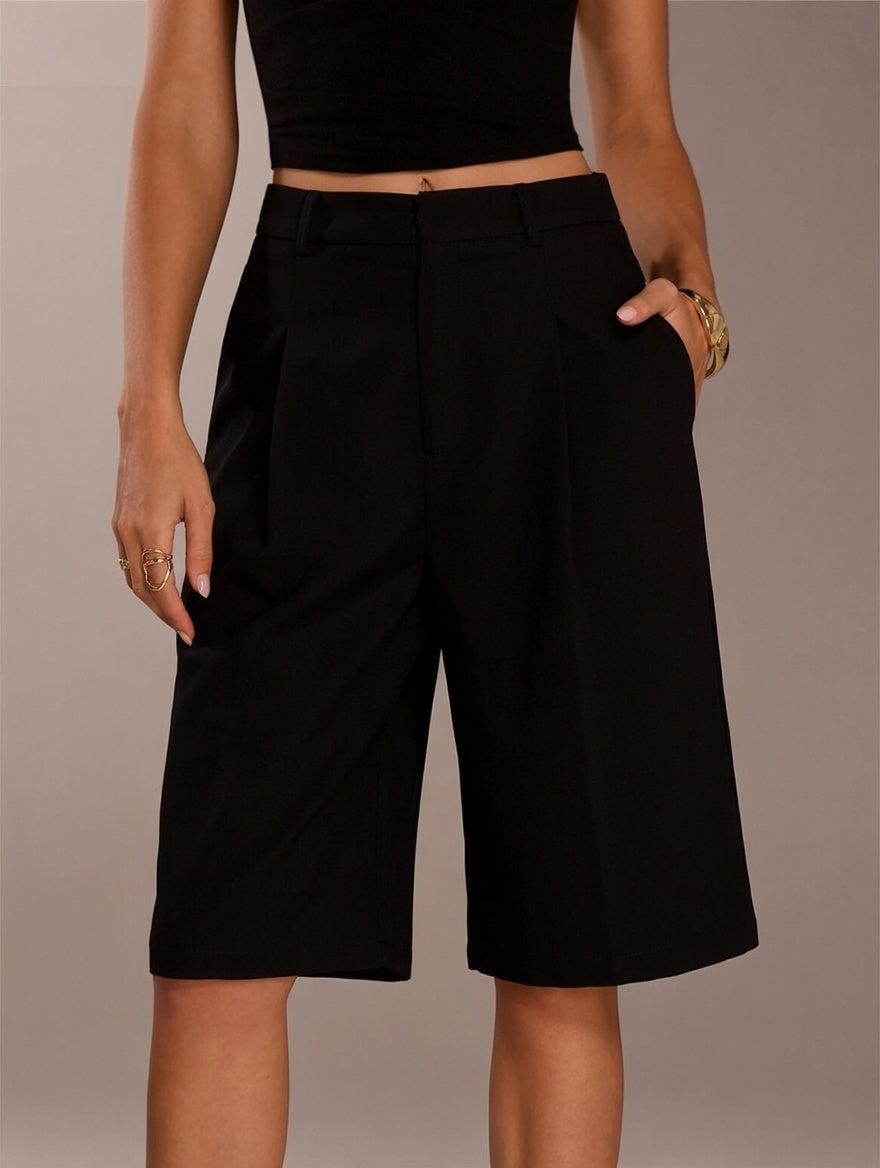 Person wearing black shorts on a neutral background