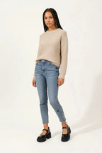 A person wearing glossy black Mary Jane platform shoes with chunky lug soles and buckle straps, paired with light blue cropped jeans on a clean white studio background.
