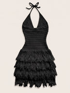 A black crochet halter mini dress with a tiered feathered skirt, displayed against a solid light beige background.
