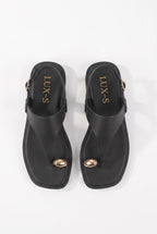 A pair of black thong-style slide sandals with small gold-tone oval hardware on the toes and gold 'LUX-S' branding on the inner sole, shown from a top-down view on a white background.