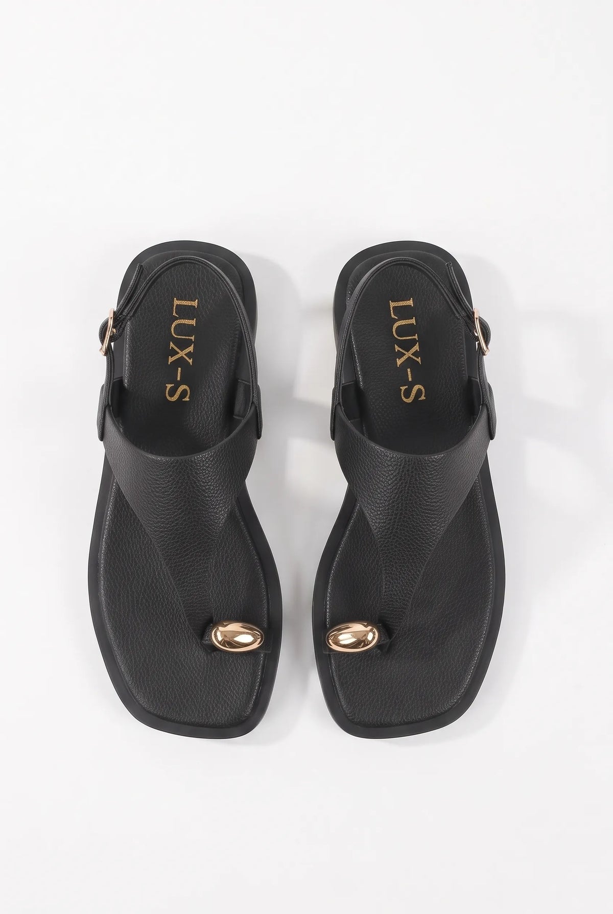 A pair of black thong-style slide sandals with small gold-tone oval hardware on the toes and gold 'LUX-S' branding on the inner sole, shown from a top-down view on a white background.