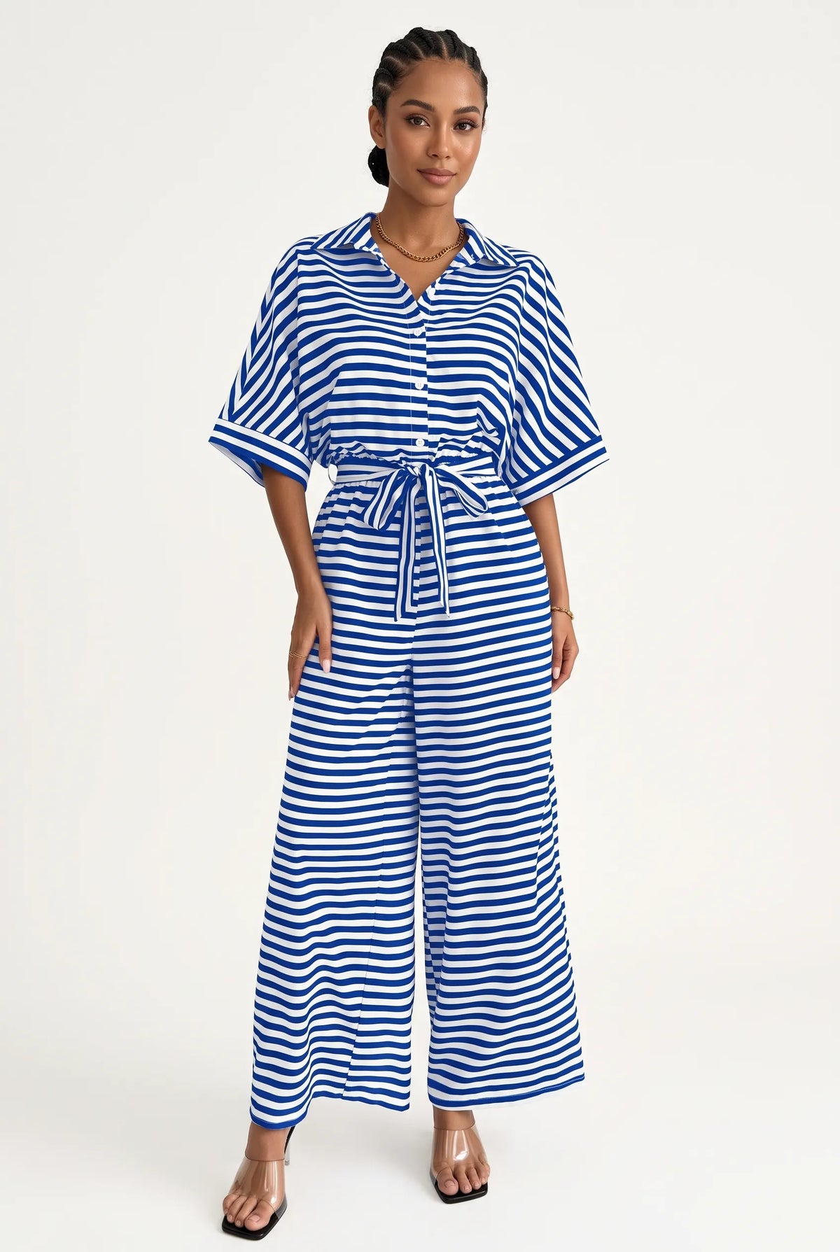 A woman modeling a blue and white horizontally striped short-sleeve jumpsuit with a matching tie belt, photographed against a plain light background.