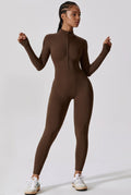A model wearing a brown long-sleeve mock-neck full-zip bodysuit, paired with white sneakers, standing against a light gray studio background.