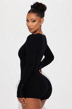 Woman wearing a black long-sleeve romper on a white background