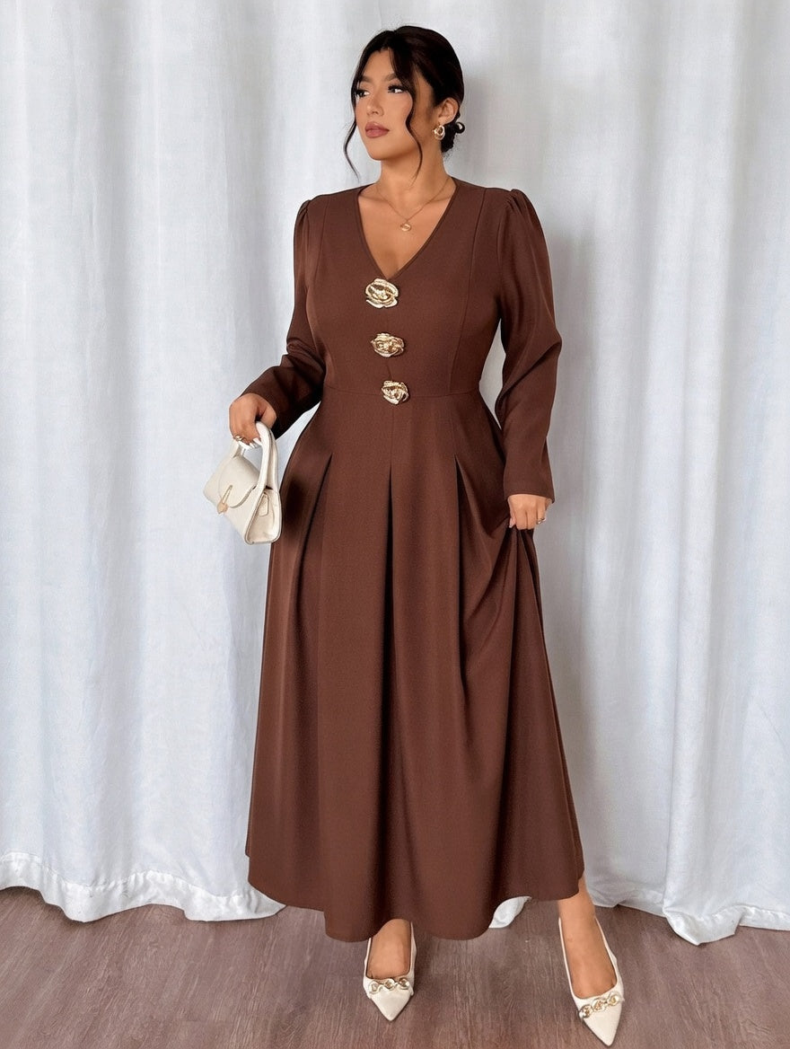 Woman wearing a brown dress with gold buttons against a white curtain background