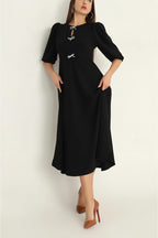 Woman wearing a black dress with white accents on a plain background