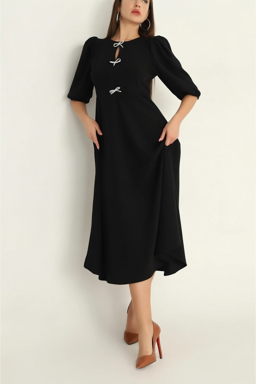 Woman wearing a black dress with white accents on a plain background