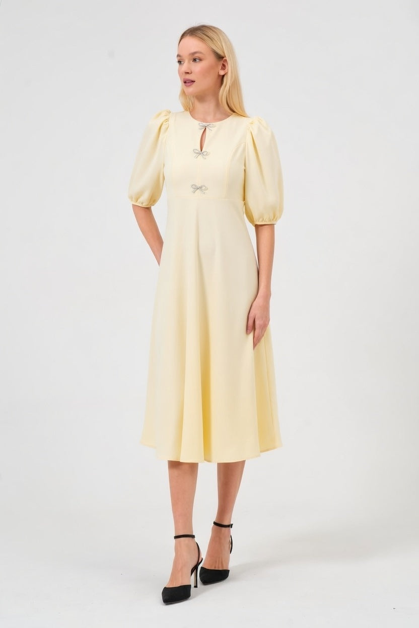 Woman wearing a light yellow dress with puff sleeves on a white background