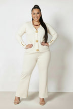 Woman wearing a white outfit with gold buttons against a white background