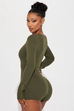 Woman wearing a green ribbed dress against a white background