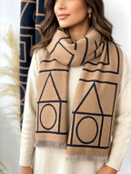 Person wearing a beige scarf with geometric patterns on a neutral background