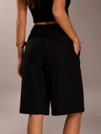 Person wearing black shorts on a plain background