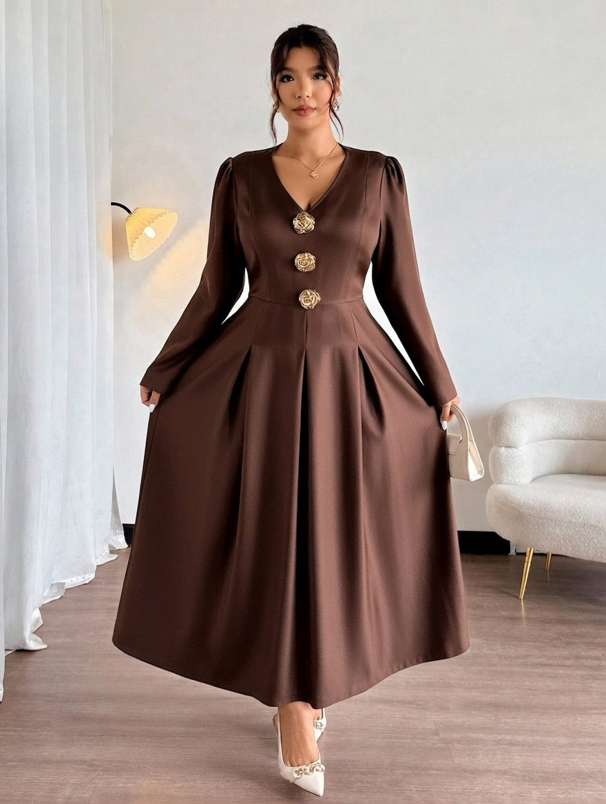 Woman wearing a brown dress with gold buttons in a room with a white sofa and lamp.
