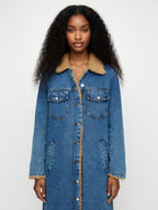 Woman wearing a long denim coat with beige lining on a white background