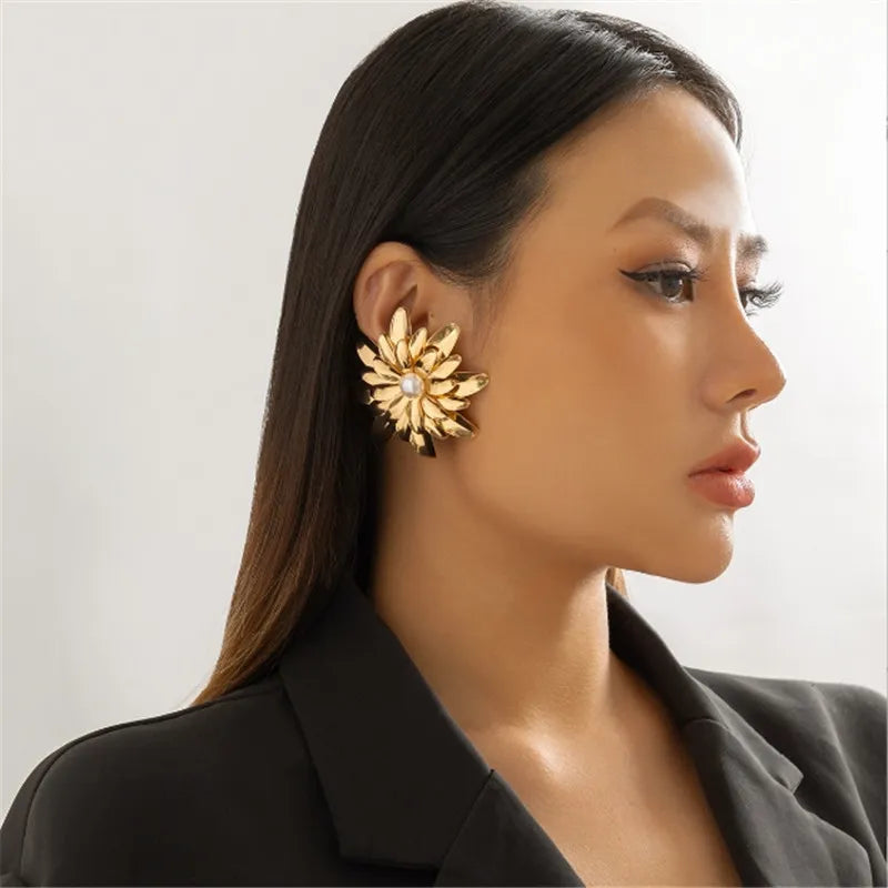 Woman wearing a gold floral earring against a neutral background