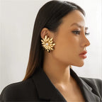 Woman wearing a gold floral earring against a neutral background