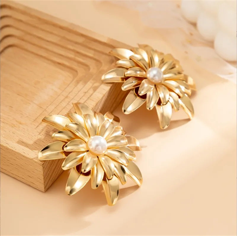 Gold earrings with pearl centers on a wooden surface
