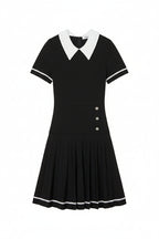 Black dress with white collar and buttons on a light gray background