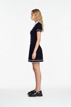 Woman wearing a black dress with white trim on a light gray background