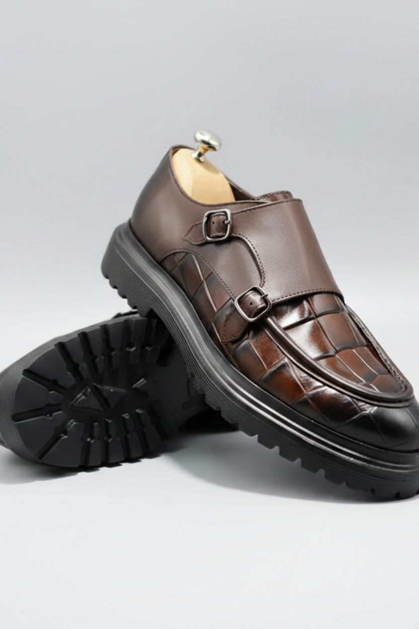 Brown leather shoes with black soles on a light gray background