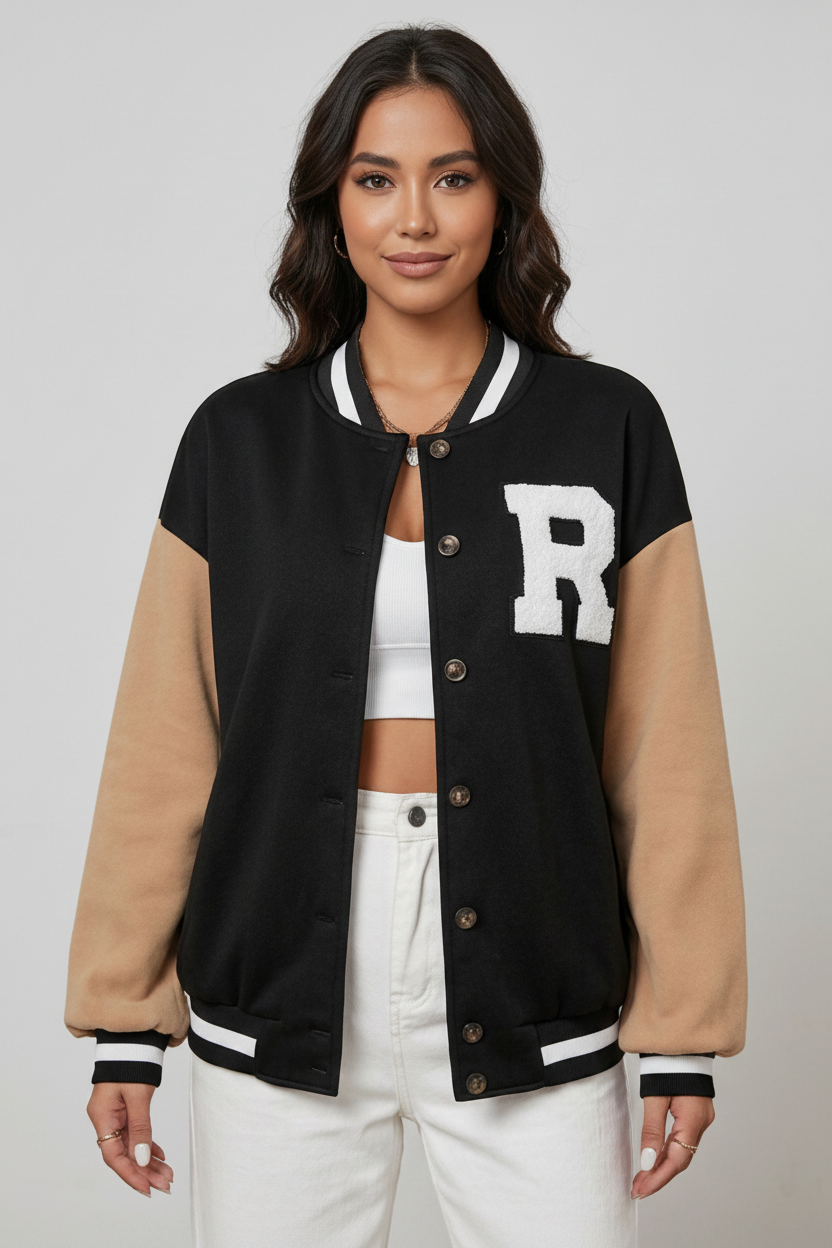 Woman wearing a black and beige varsity jacket with a large white letter 'R' on a gray background
