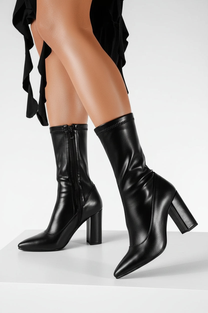 Black knee-high boots worn by a person on a neutral background