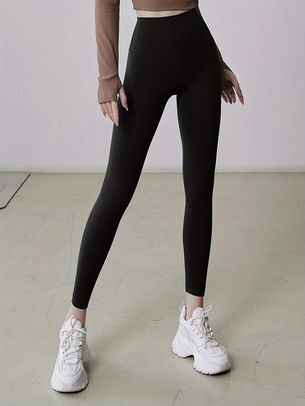 Person wearing black leggings and white sneakers on a plain background